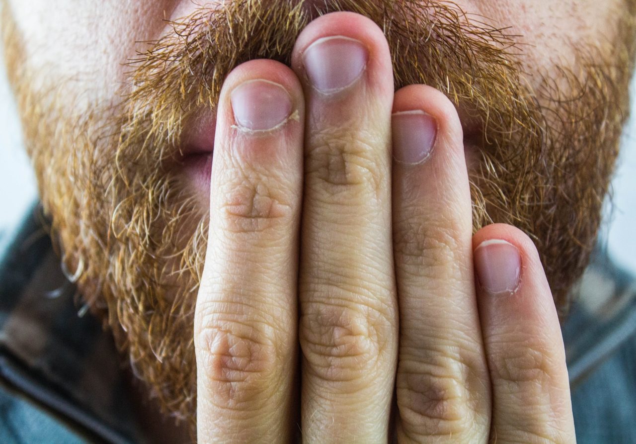 man with beard holding hand up to mouth