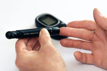 Person pricking their finger to check their blood sugar with a diabetes monitor