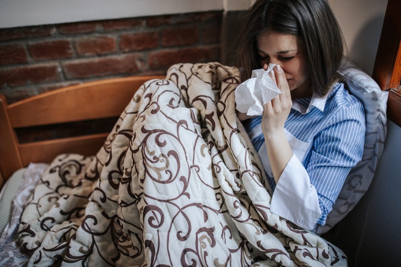 Young sick woman,Infected with a virus, sitting in bed and blowing nose