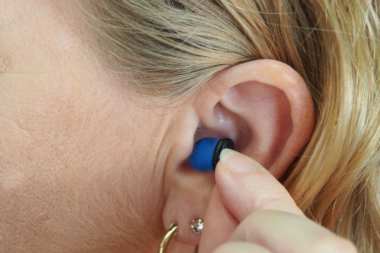 Woman putting on earplugs.