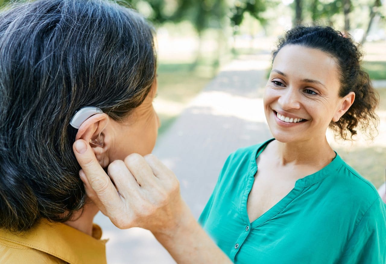 Woman with hearing aid chatting with her friend outside.