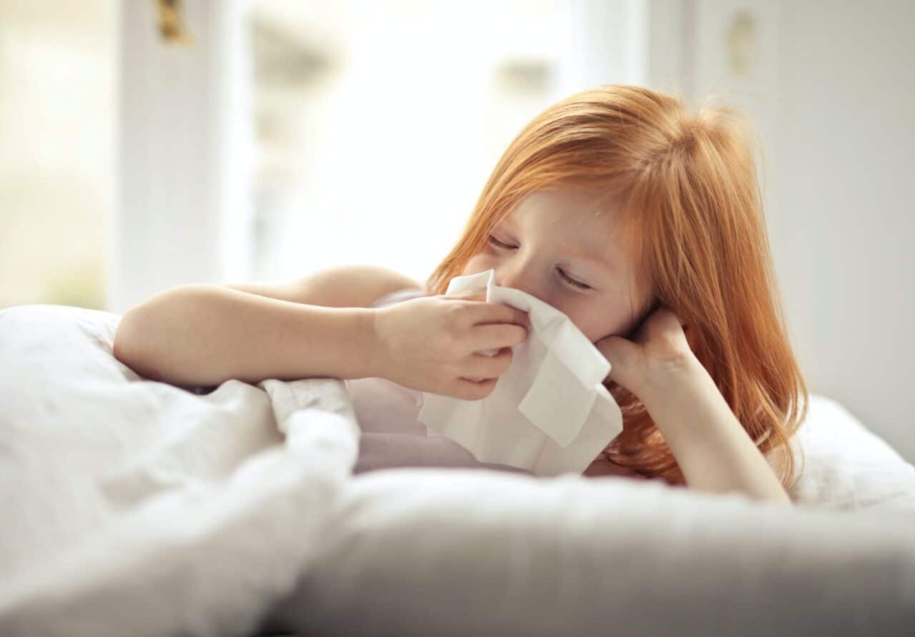 Young girl blowing her nose.