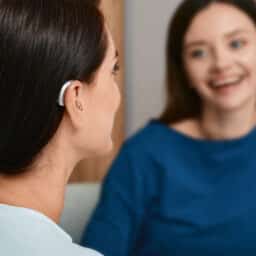 Woman with hearing aids chatting with her friend indoors.