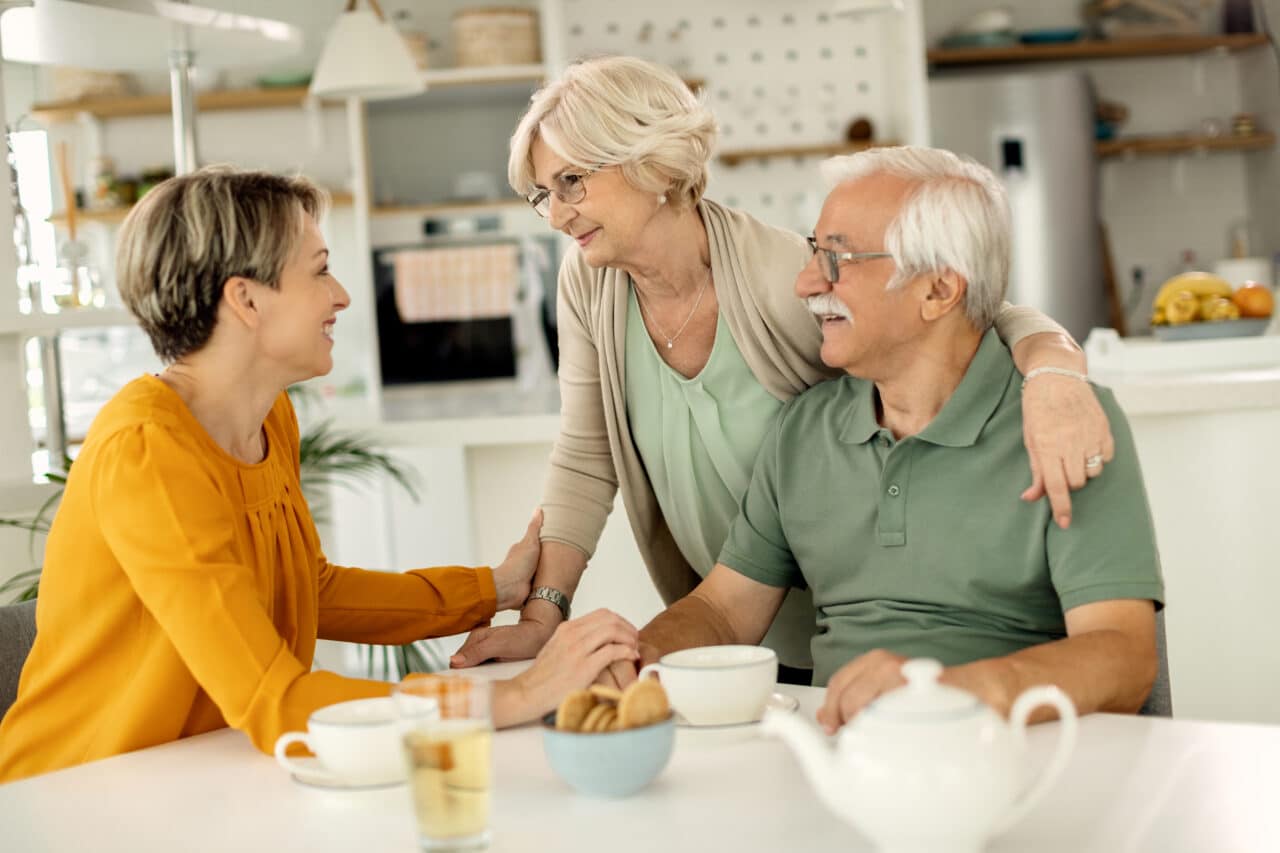 Woman visiting her senior parents and communicating with them at home.