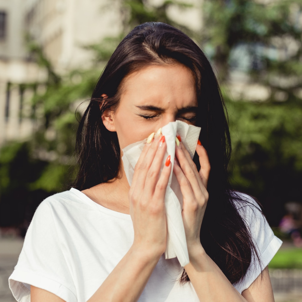 a woman in the park blows her nose