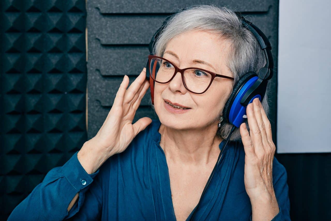 Senior woman wearing headphones while getting a hearing test.