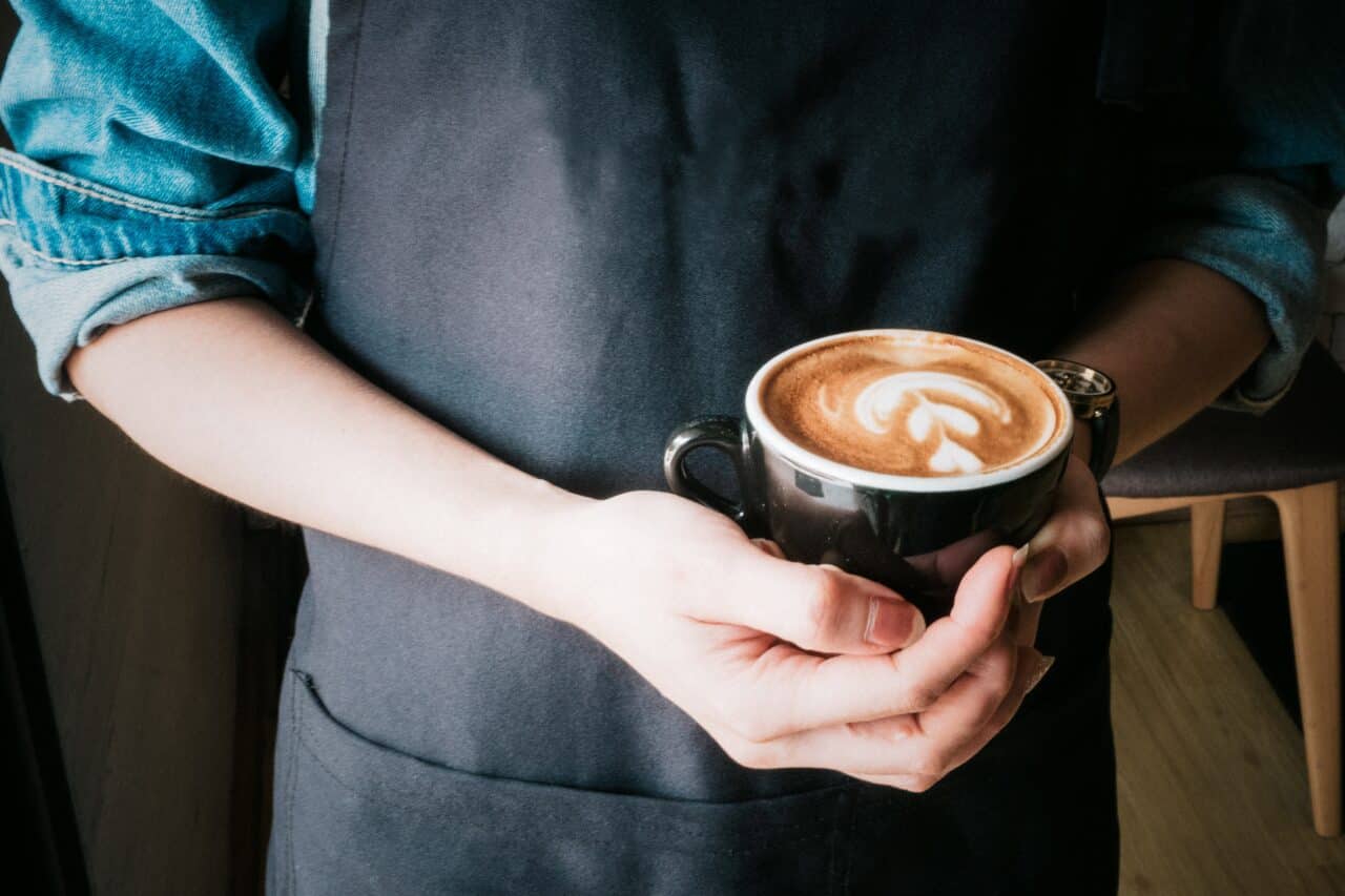 Woman holding a mug of cappuccino.