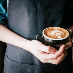Woman holding a mug of cappuccino.