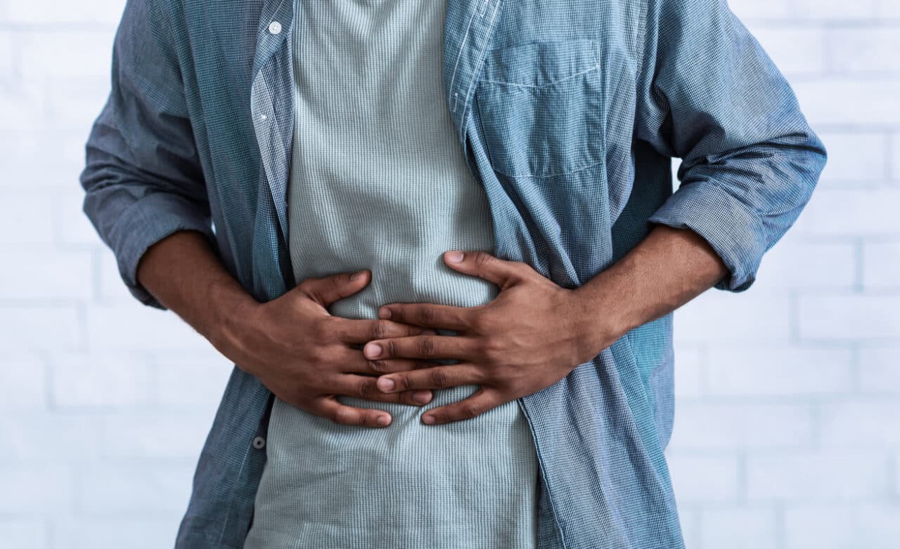 Close up of a man holding his stomach.