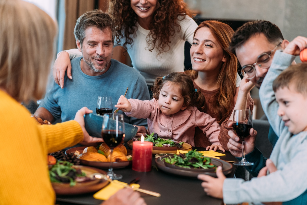 Happy extended family celebrating Thanksgiving at dining table.