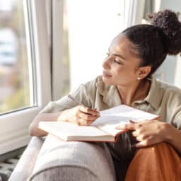 Happy woman journaling and looking out the window