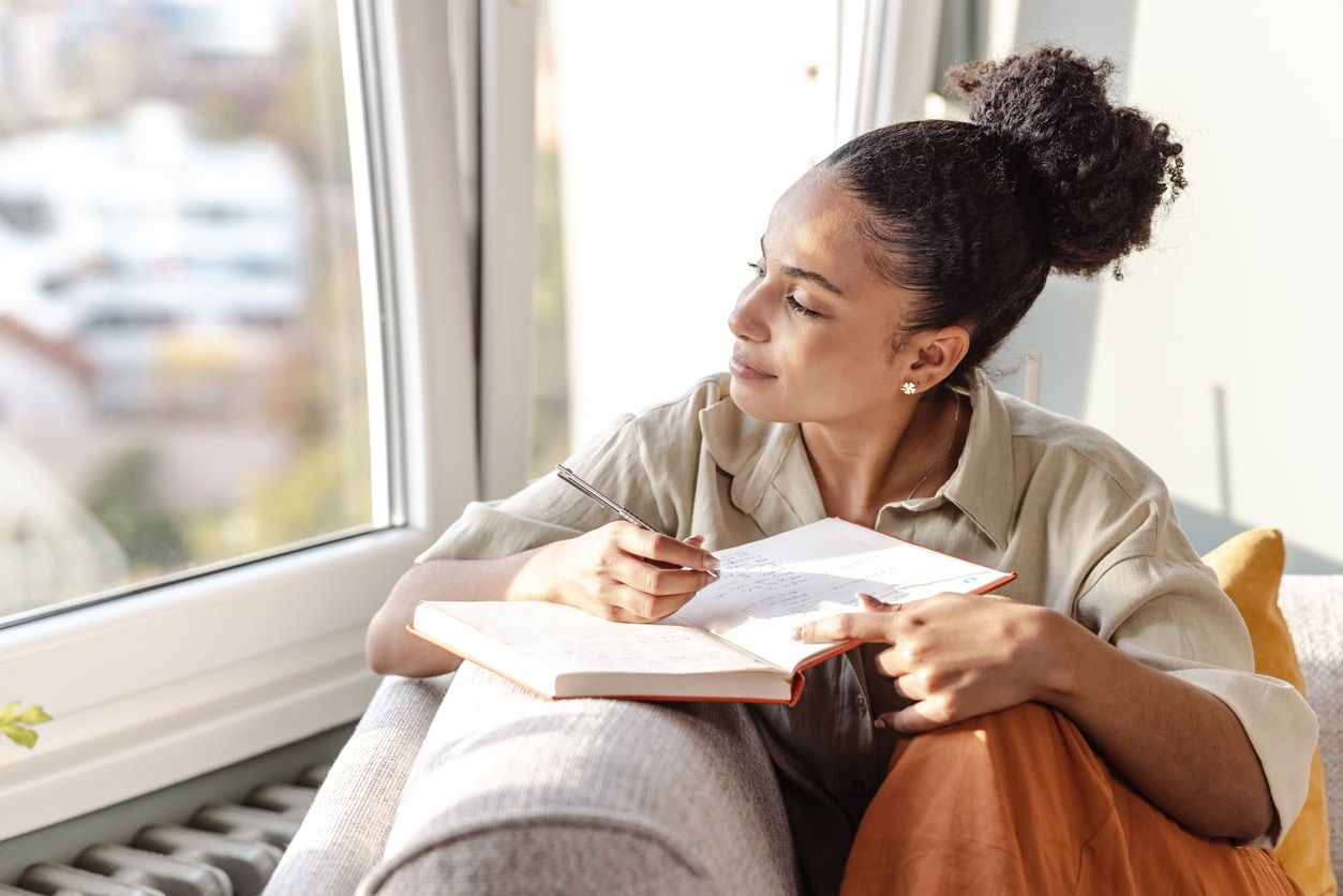 Happy woman journaling and looking out the window.