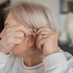 Senior woman putting in a hearing aid