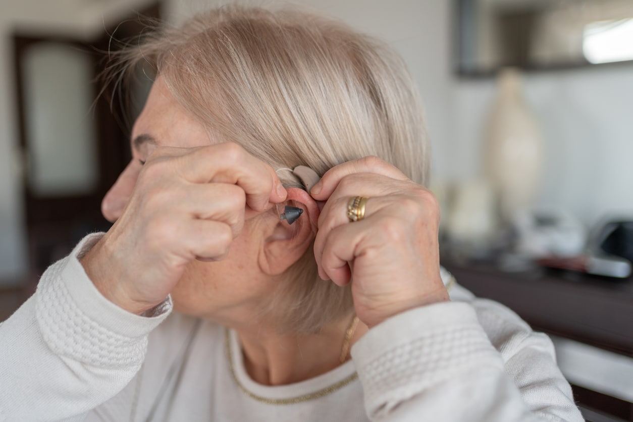 Senior woman putting in a hearing aid.