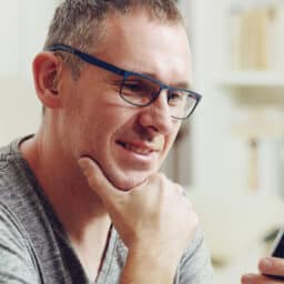 Man with hearing aid looks at phone