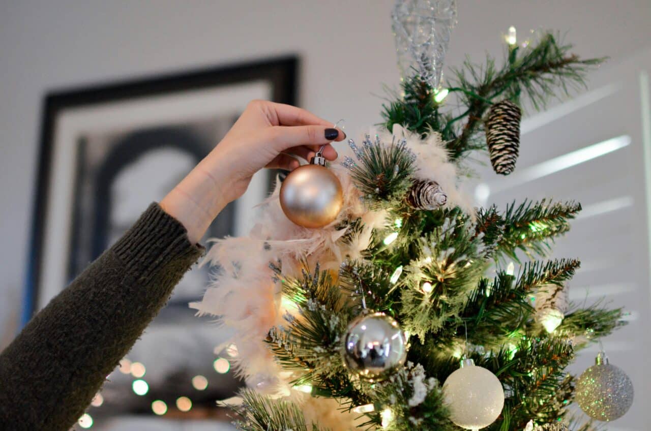 Close up of hand hanging an ornament high on a Christmas tree